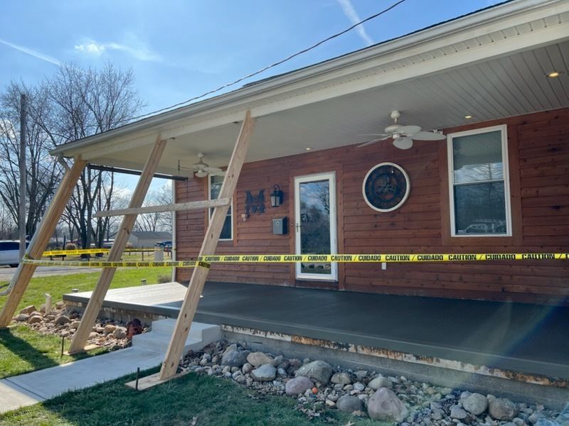 A rectangular pool with light blue water and a concrete deck; two houses and trees in the background.