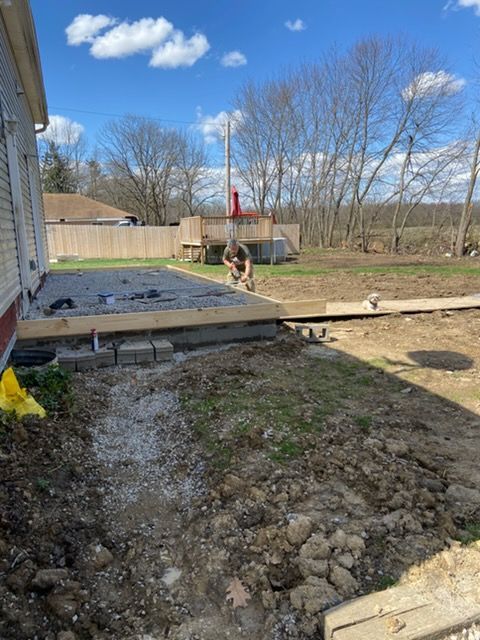 Empty swimming pool with blue speckled lining and steps. Concrete patio surrounds it, houses in background.