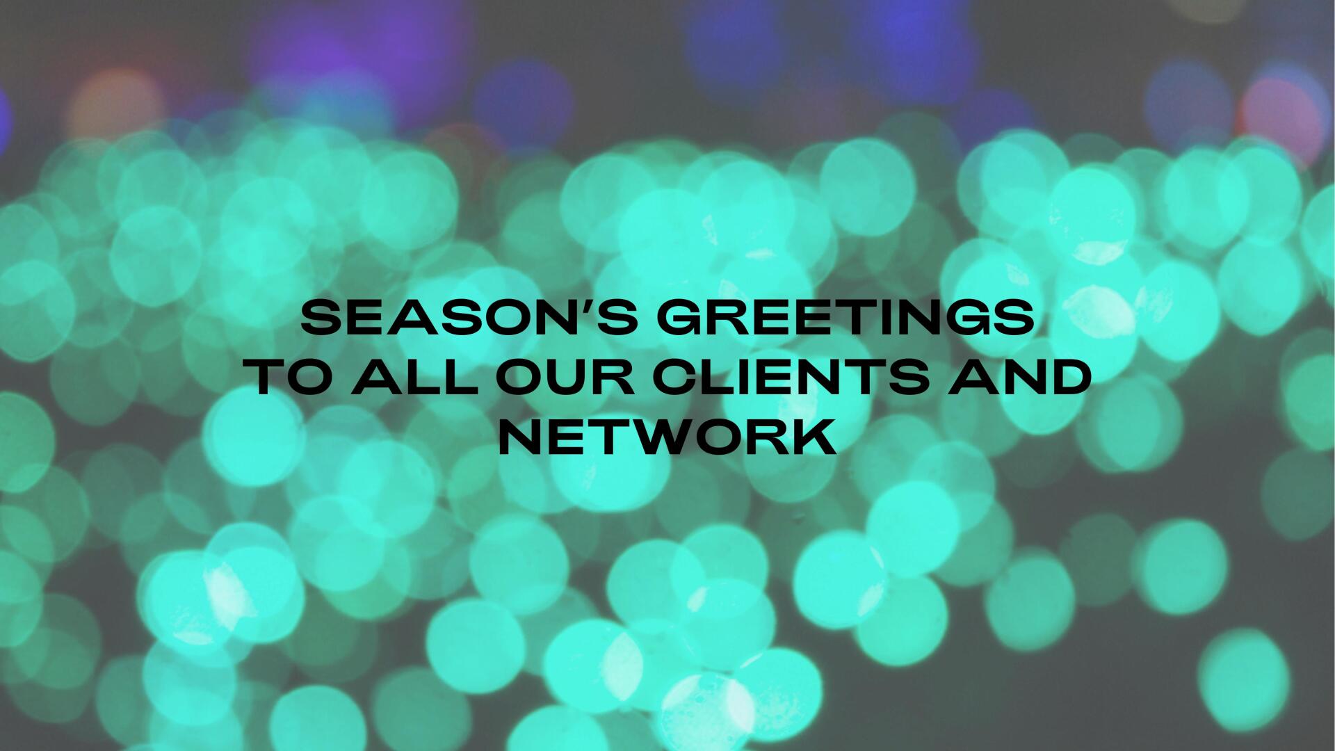 A background of blurred blue green lights with the words Seasons greetings printed in black