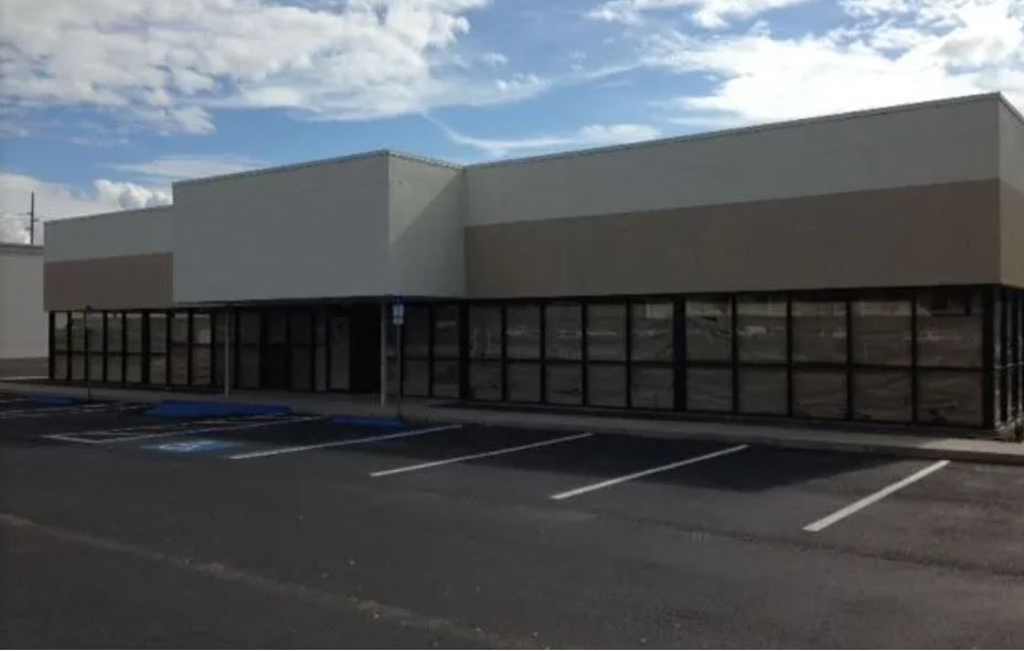 A building with a lot of windows and a parking lot in front of it