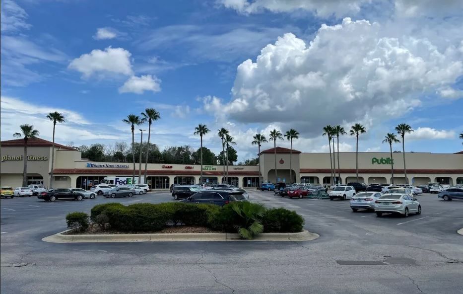 A lot of cars are parked in front of a shopping center.