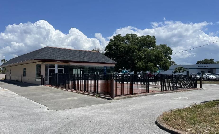 A building with a fence around it and a lot of cars parked in front of it.