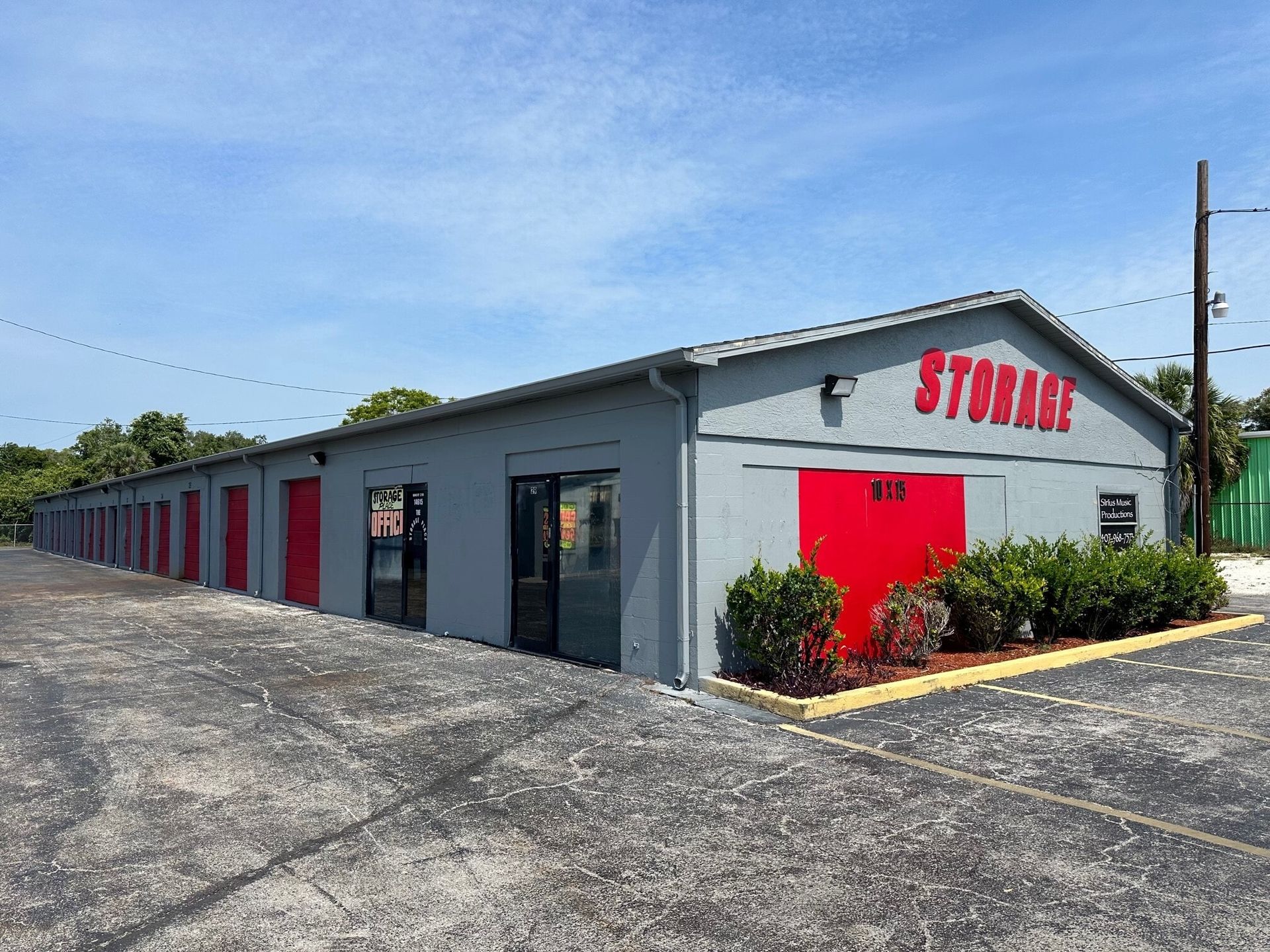 A row of gray buildings with red doors and a sign that says `` storage ''.