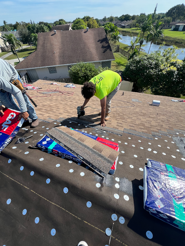 A man in a neon green shirt is working on a roof.