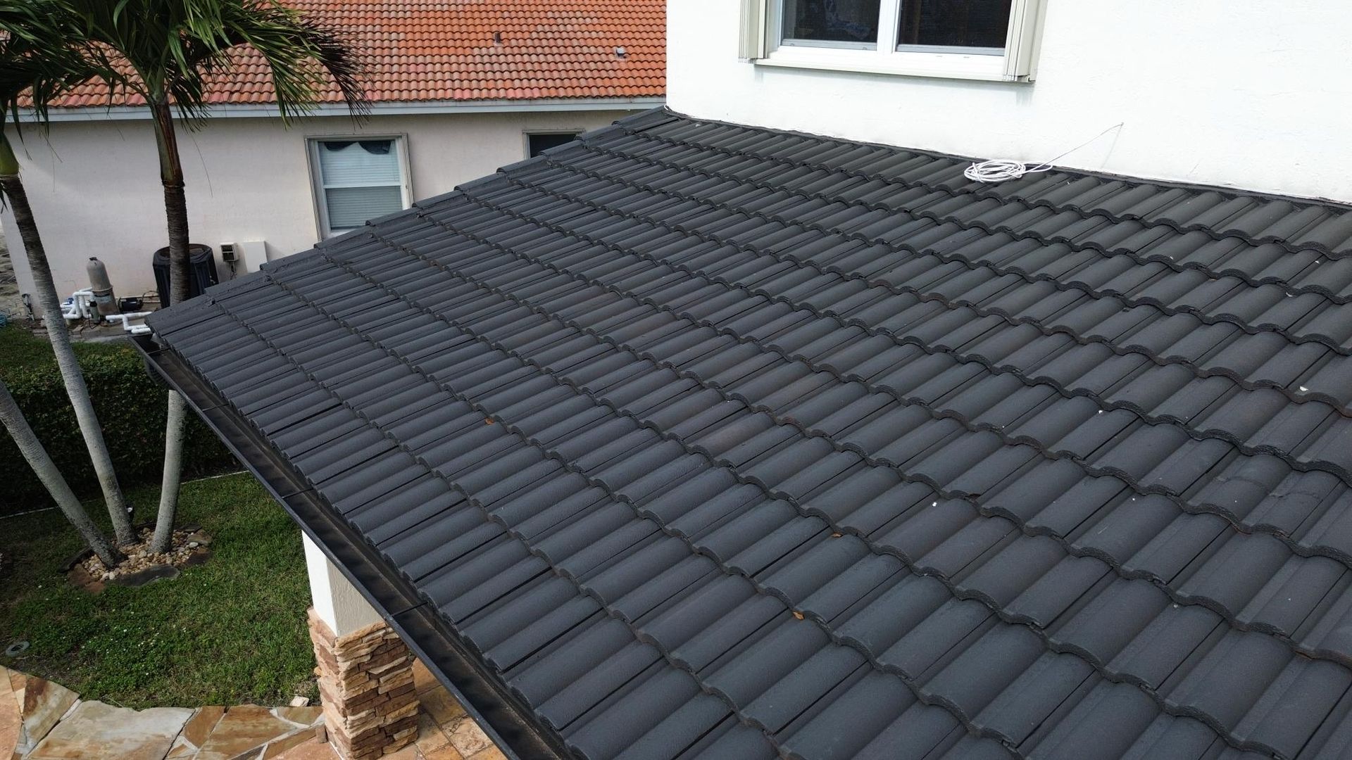 A black tile roof is sitting on top of a white house.