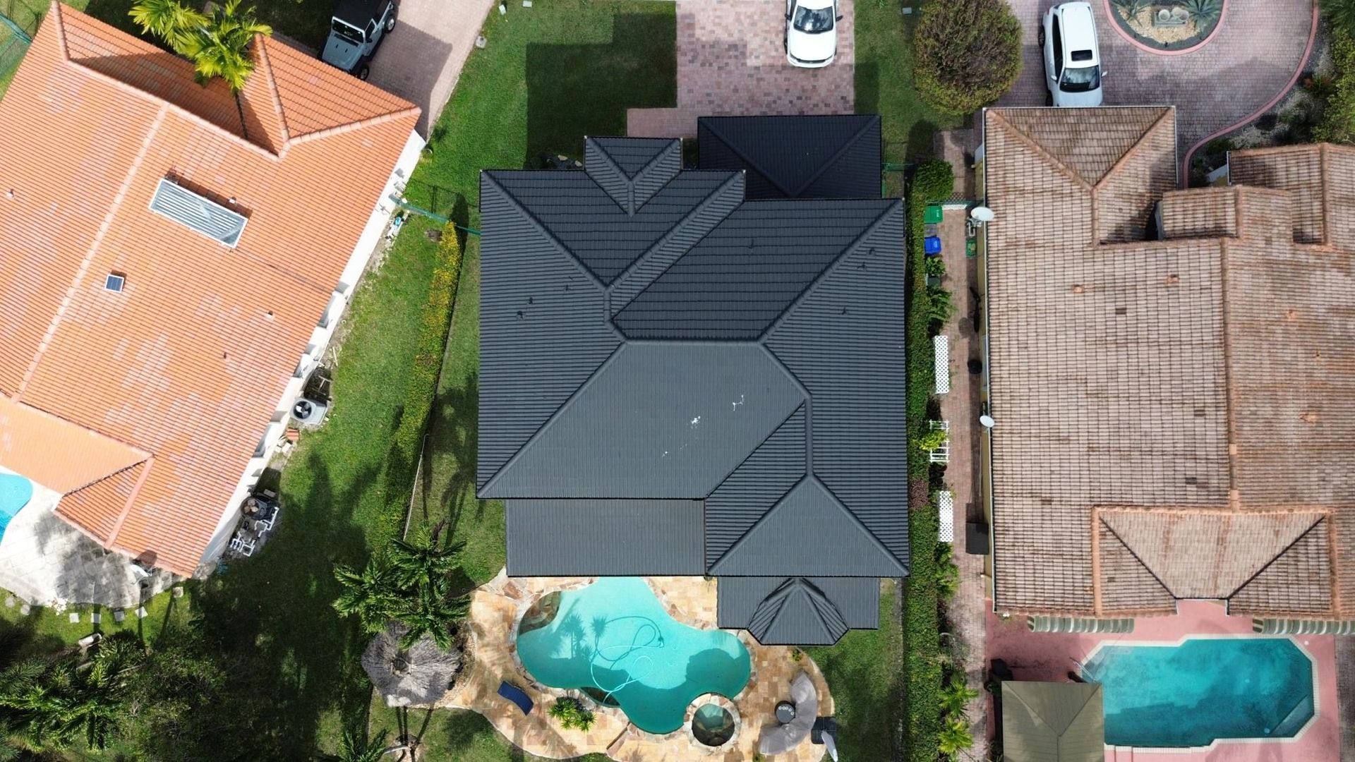 An aerial view of a house with a black roof and a pool