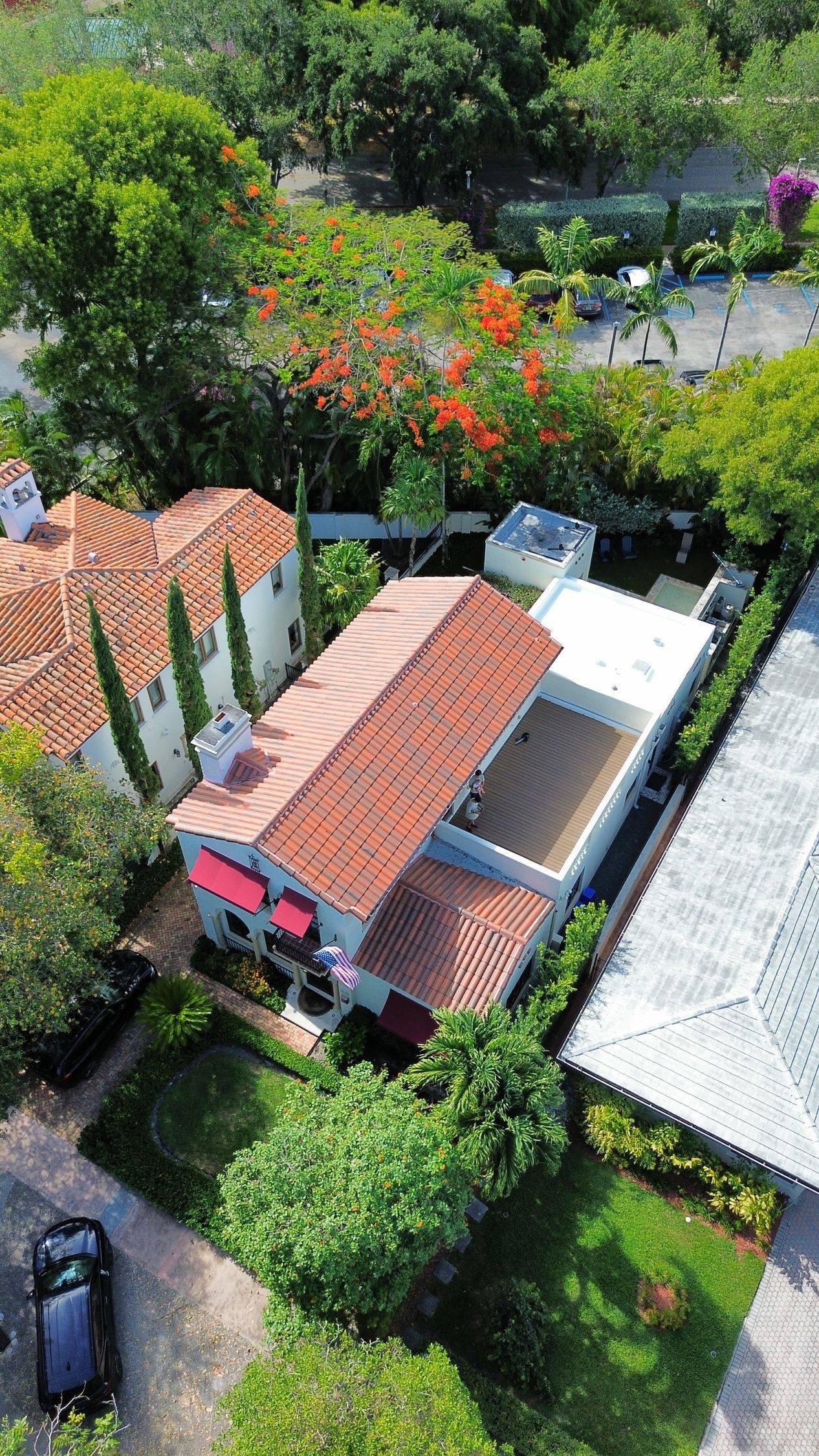 An aerial view of a house with a car parked in front of it surrounded by trees.