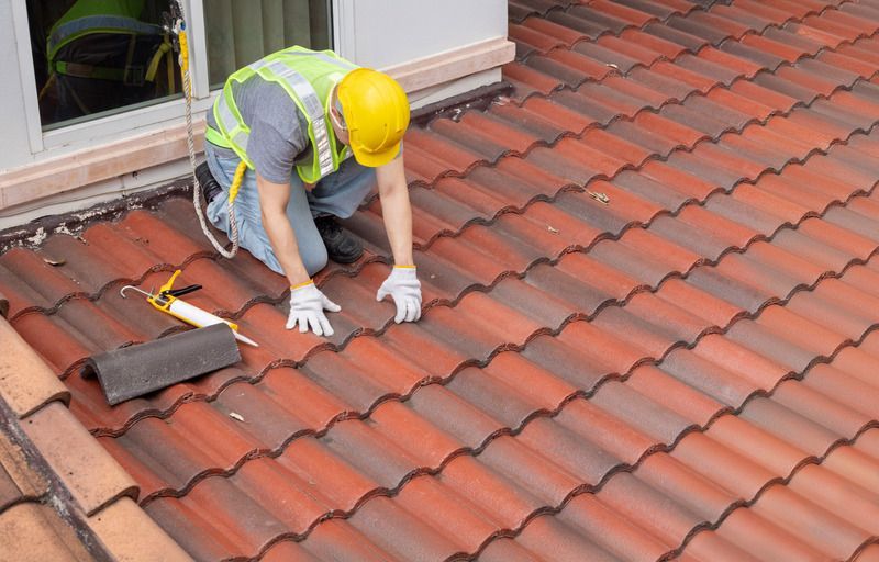 A man is working on a tiled roof.