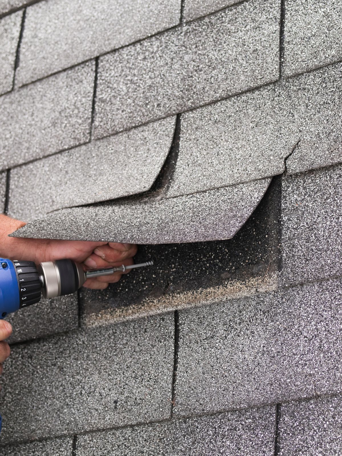 A person is using a drill to fix a hole in a roof.