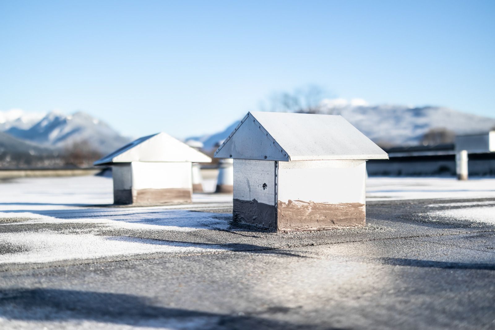 Snow-covered rooftops in a winter landscape with mountains in the background