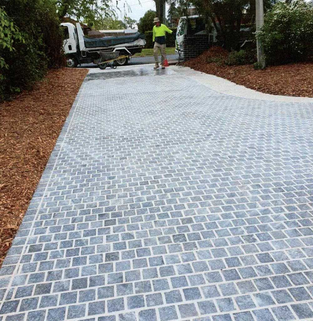 Park with green grass, concrete path, and metal shade structures on a sunny day.