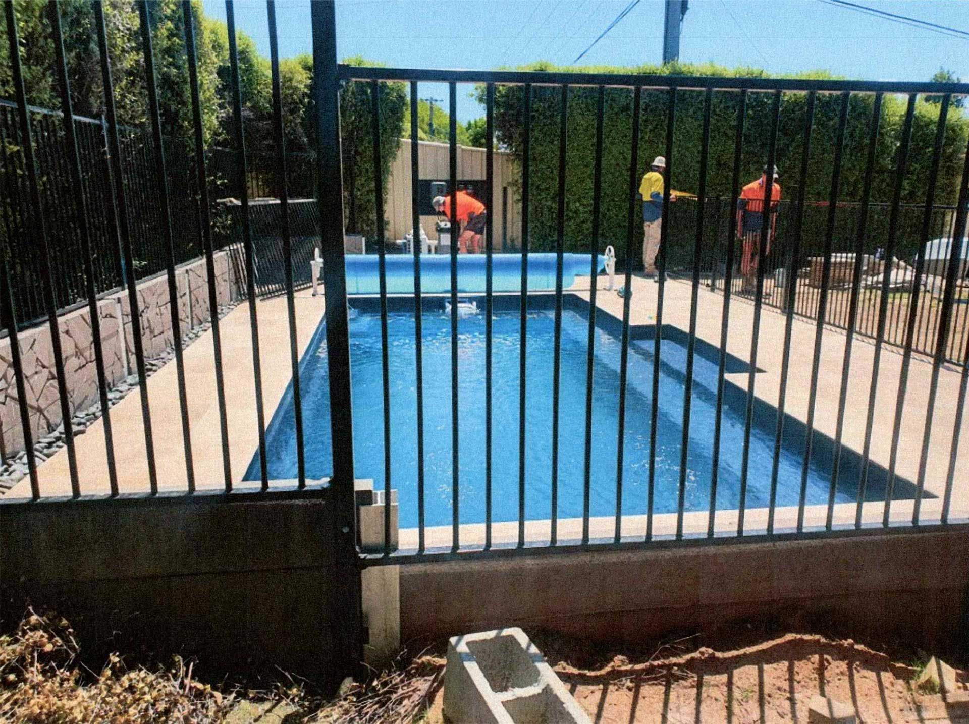 Green lawn and pathway beside a brick building, leading to a gazebo under a blue sky.