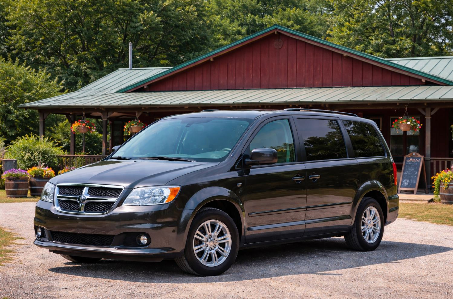 White passenger van parked in a driveway, with open side door, in front of a house and vineyard.