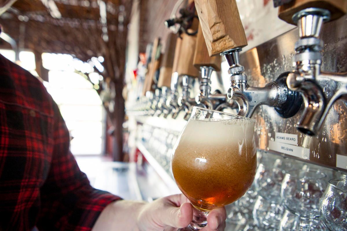 A person pours beer from a tap into a glass at a bar.