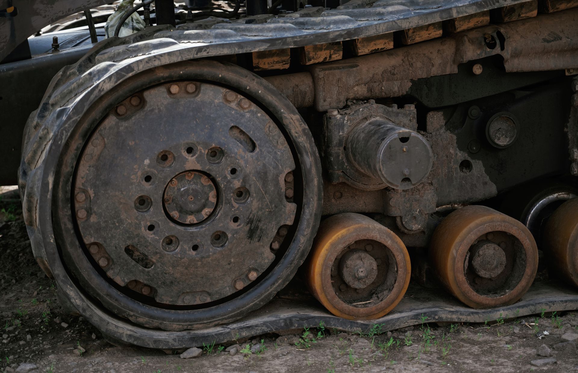 Rusty tank tread and large metal road wheels on a military vehicle chassis