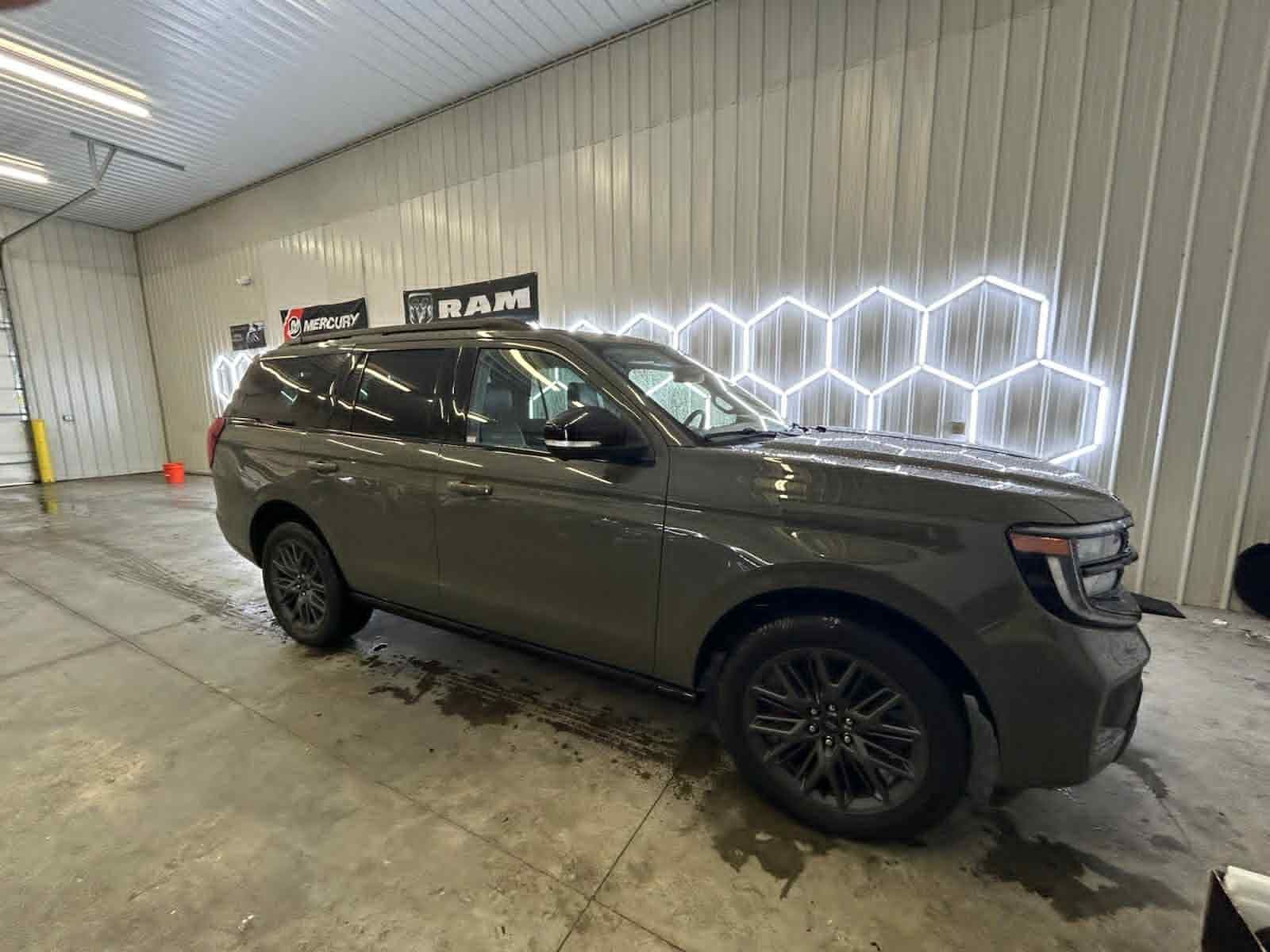 Gray Ford Expedition SUV in a car wash bay with hexagon-shaped neon lights.