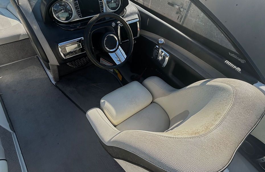 The interior of a boat with a steering wheel and a seat.