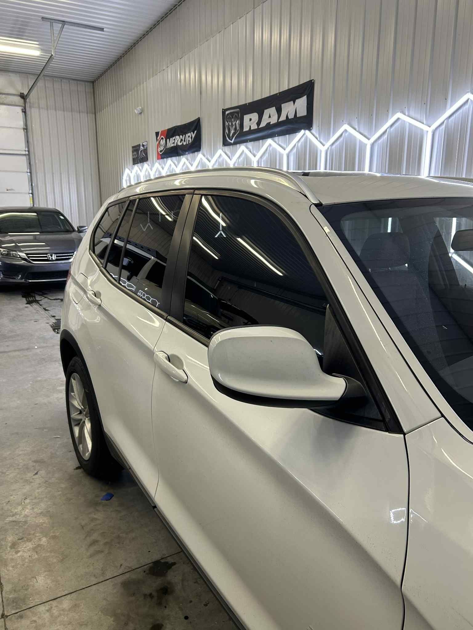 White SUV parked inside a garage; side view; glossy finish.
