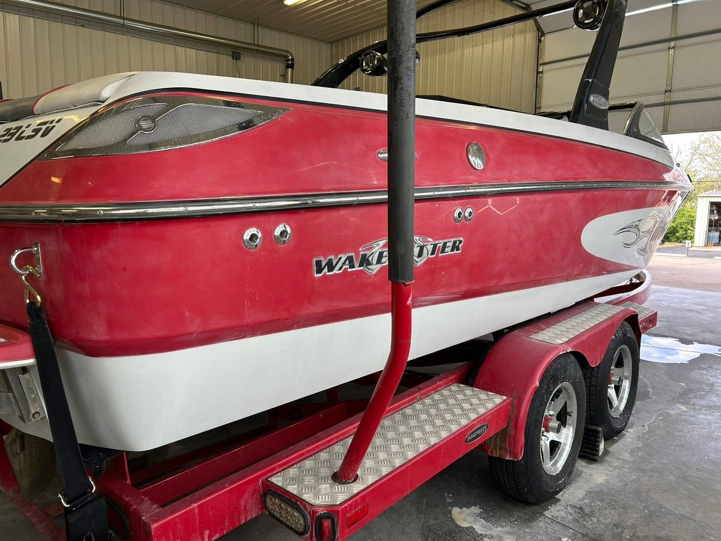 A boat with a black canopy is parked in front of a garage.