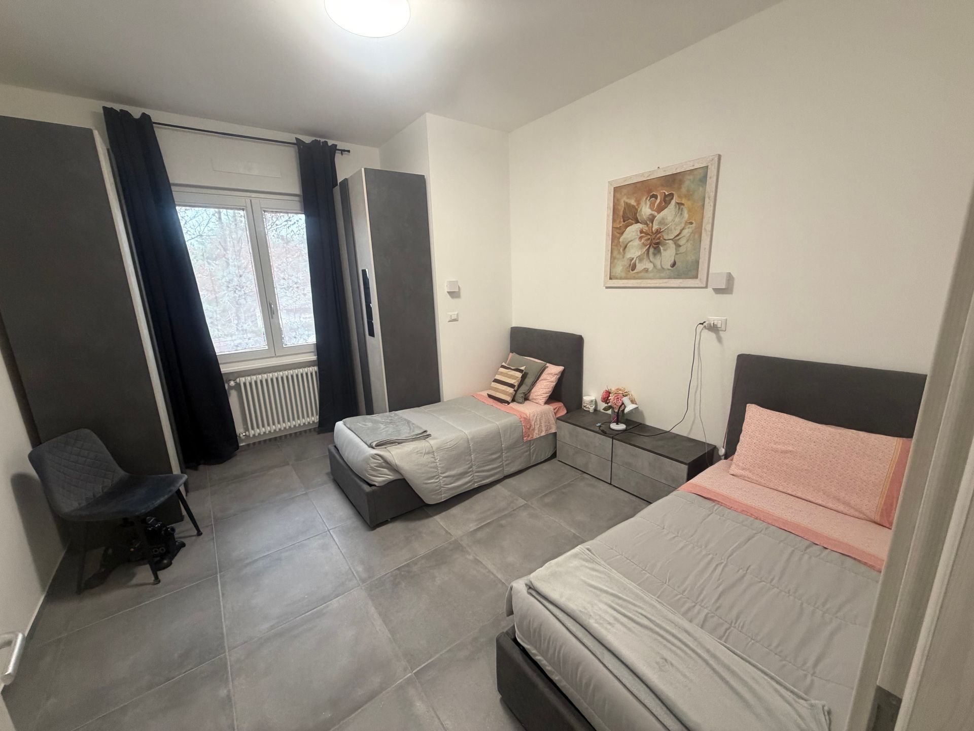 Camera da letto con due letti singoli, parete verde con decalcomanie floreali e porta-finestra.