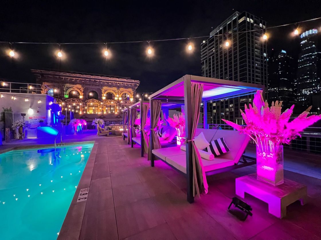 Rooftop pool deck at night with cabanas and pink lighting at HWH Luxury Living in DTLA