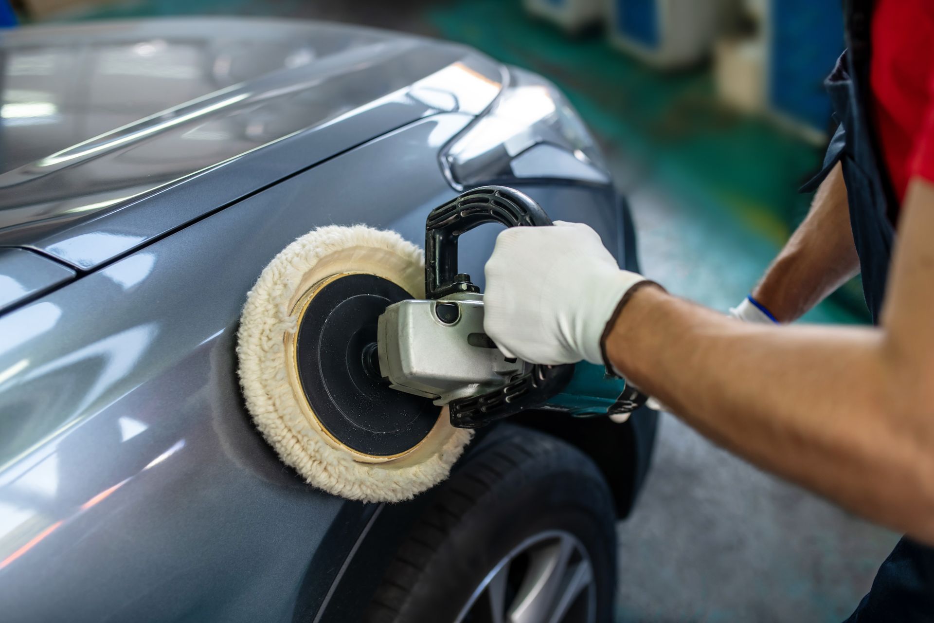 A close-up of a male hand with a polishing machine on a surface of a car.