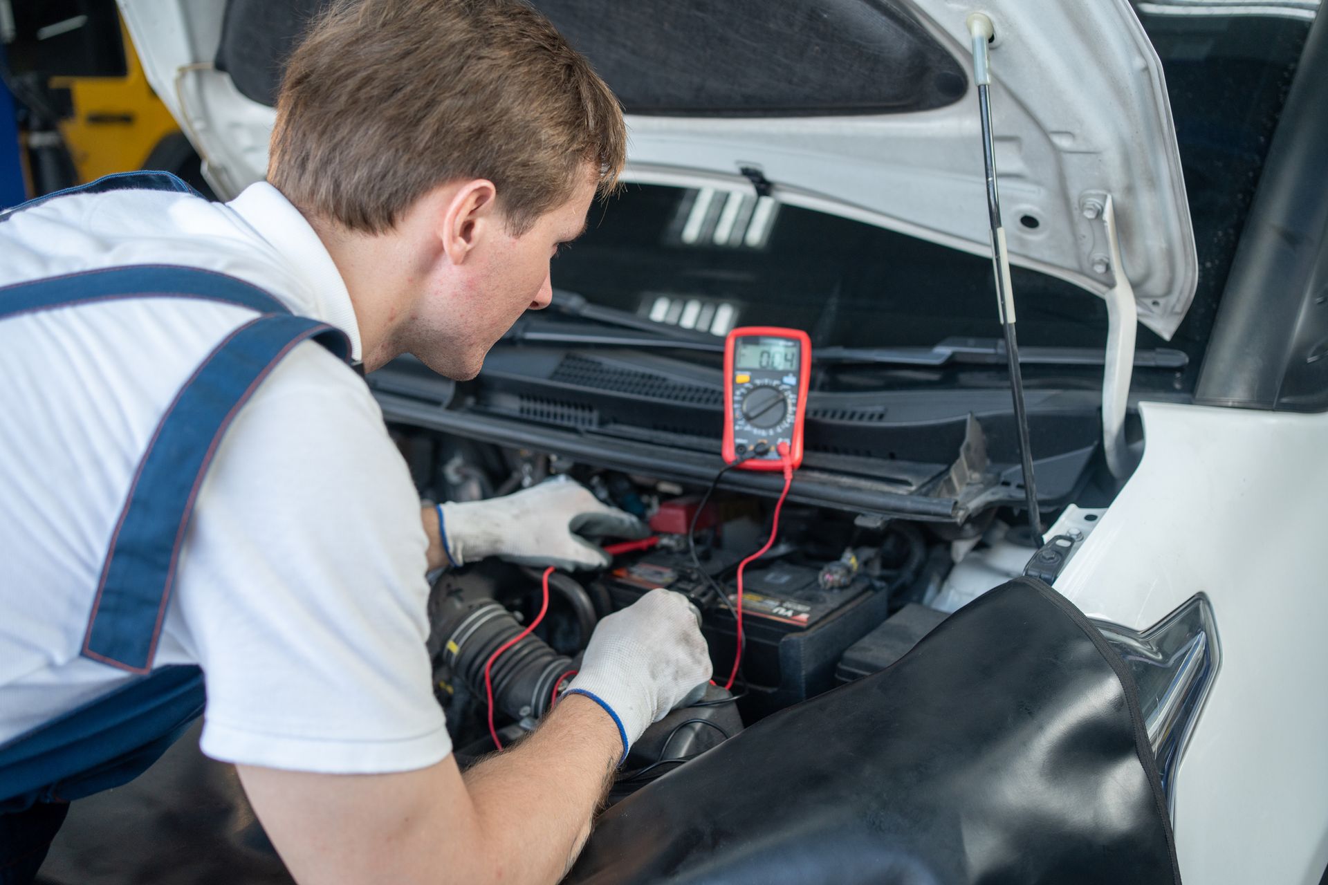 A car mechanic checking the voltage on a car battery