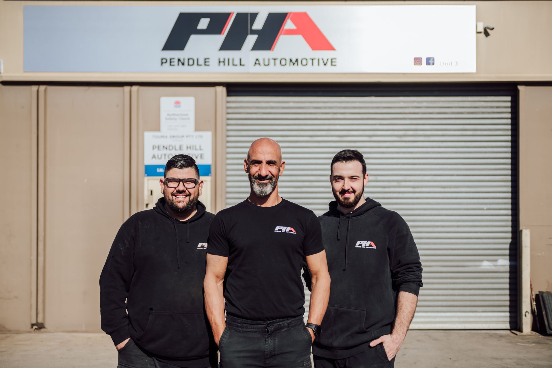 Three men in black shirts in front of the 