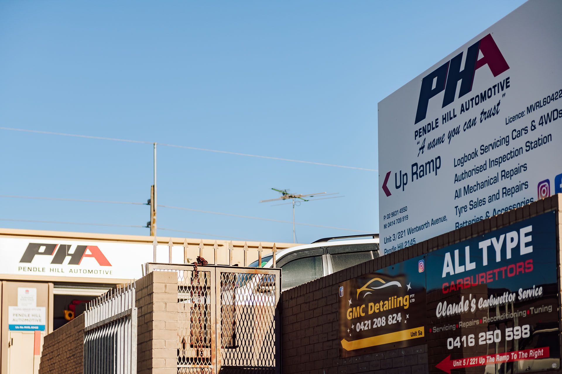Sign for PHA Vehicle & Automotive, with a plane flying overhead.