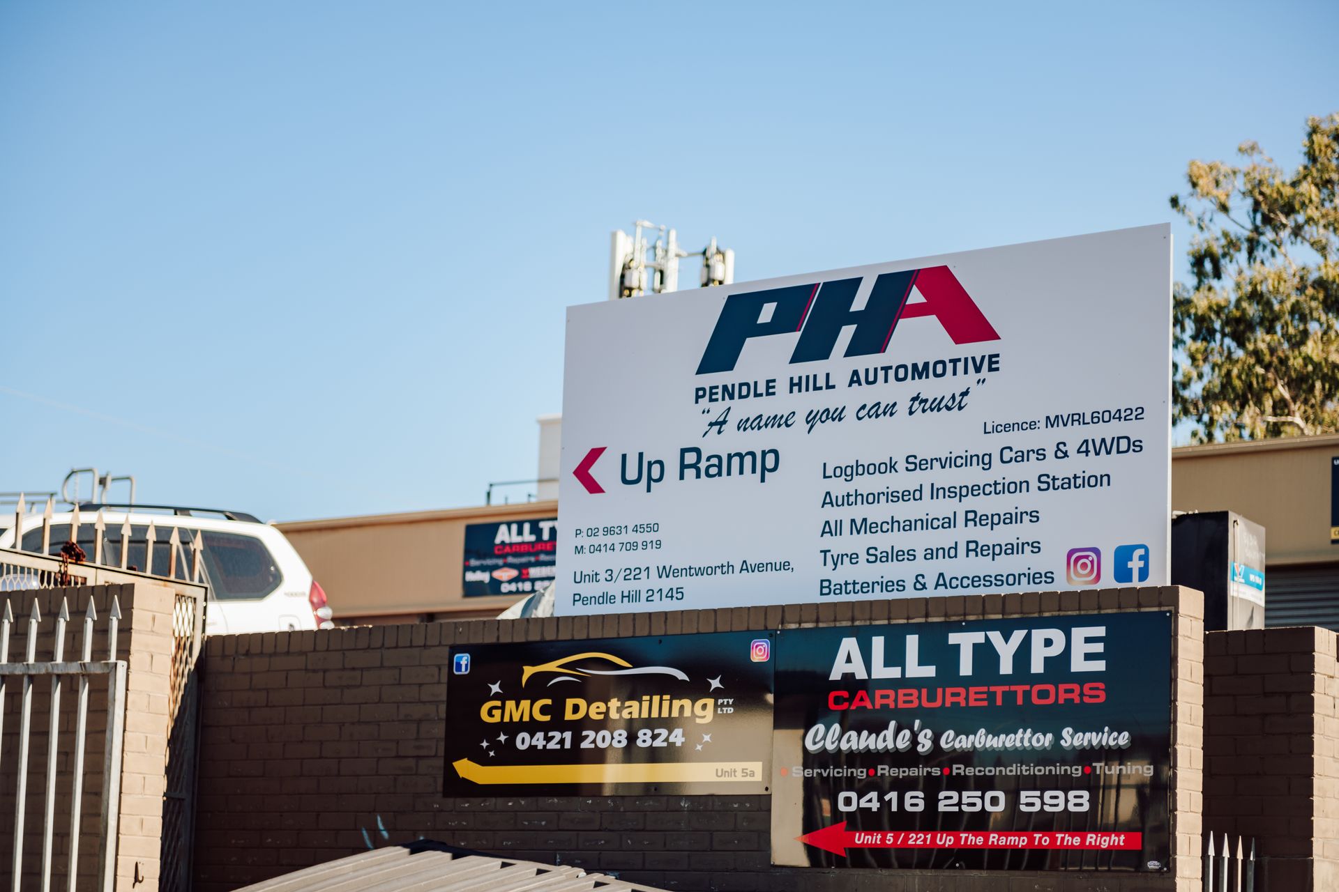 Signage for auto repair businesses, including PHA Vehicle Hill Automotive, next to a ramp.