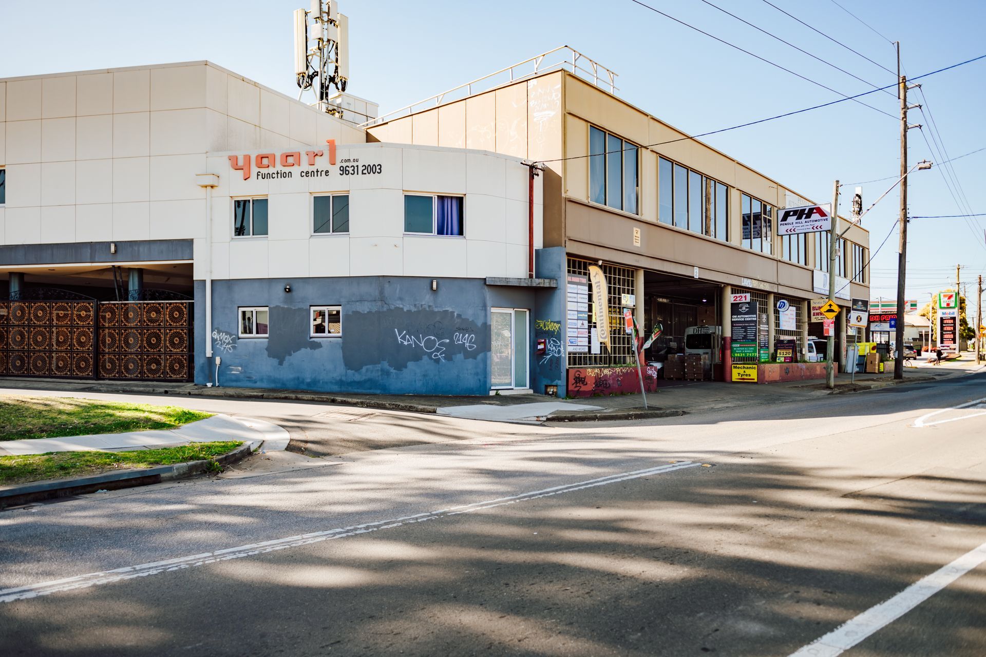 Corner building with Yaarl sign, blue and tan facades, open storefront, sunny day.