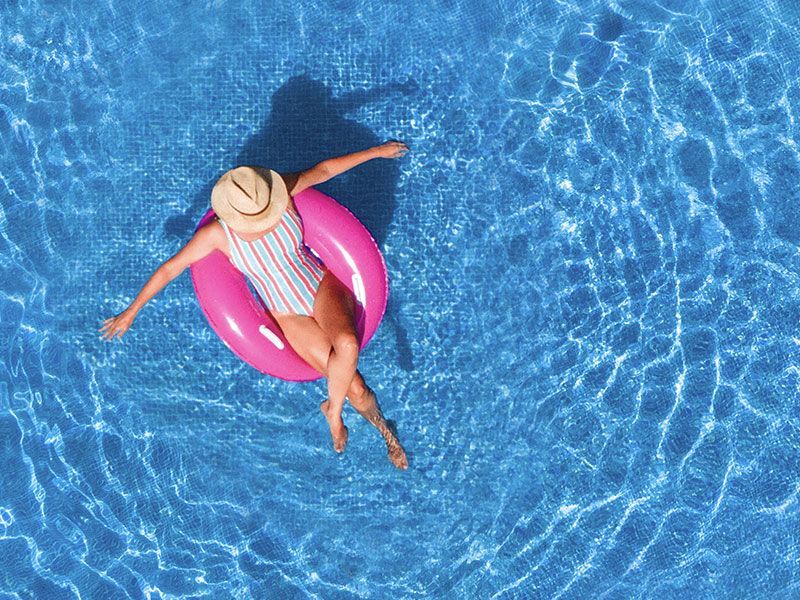 a woman is floating on a pink raft in a swimming pool .
