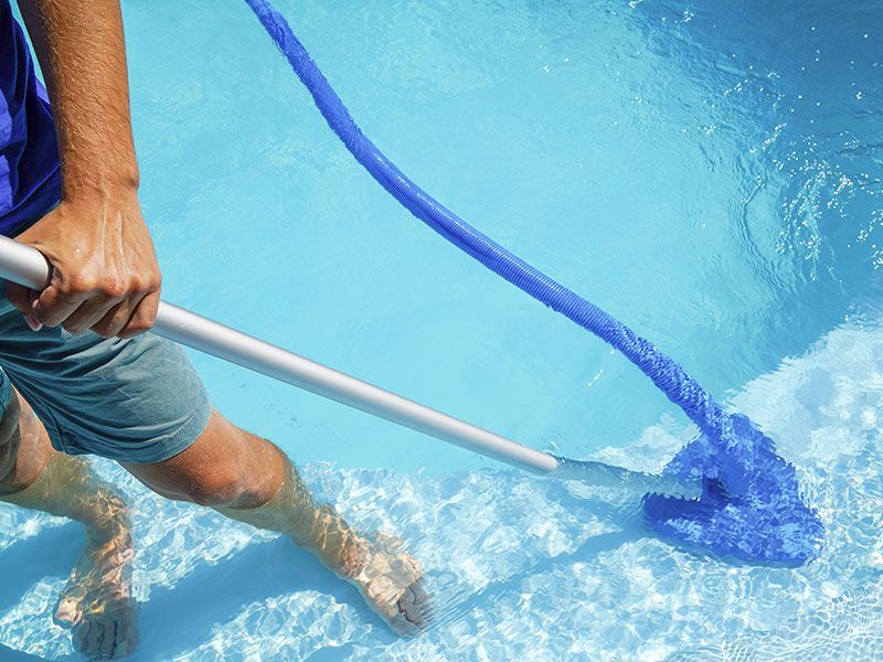 a man is cleaning a swimming pool with a broom .