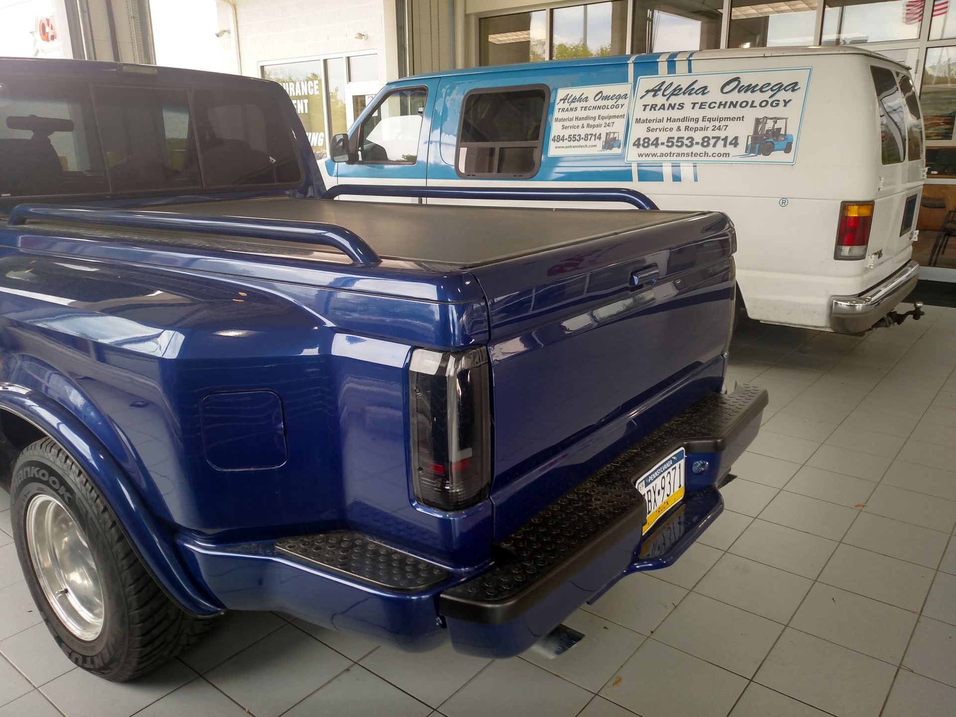 Worker in orange gloves and jacket securing metal panel on a rooftop, near train tracks.