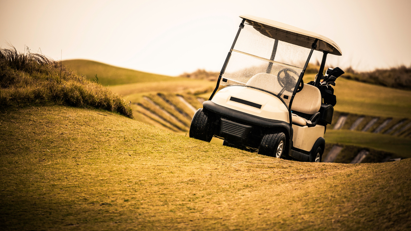 Golf cart on a steep embankment of a golf course, ready to descend.