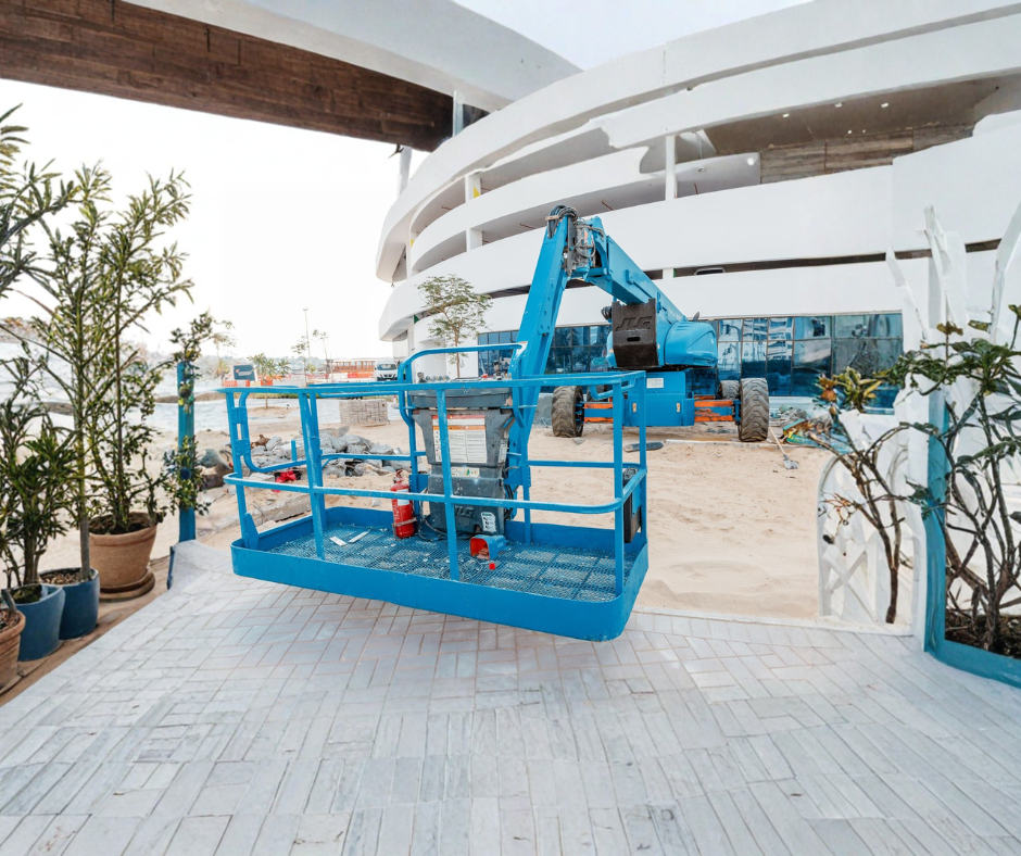 Orange forklift arm and forks against a clear blue sky.
