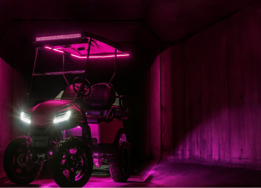 Orange and black forklift on an asphalt surface, parked outdoors with a wire fence in the background.