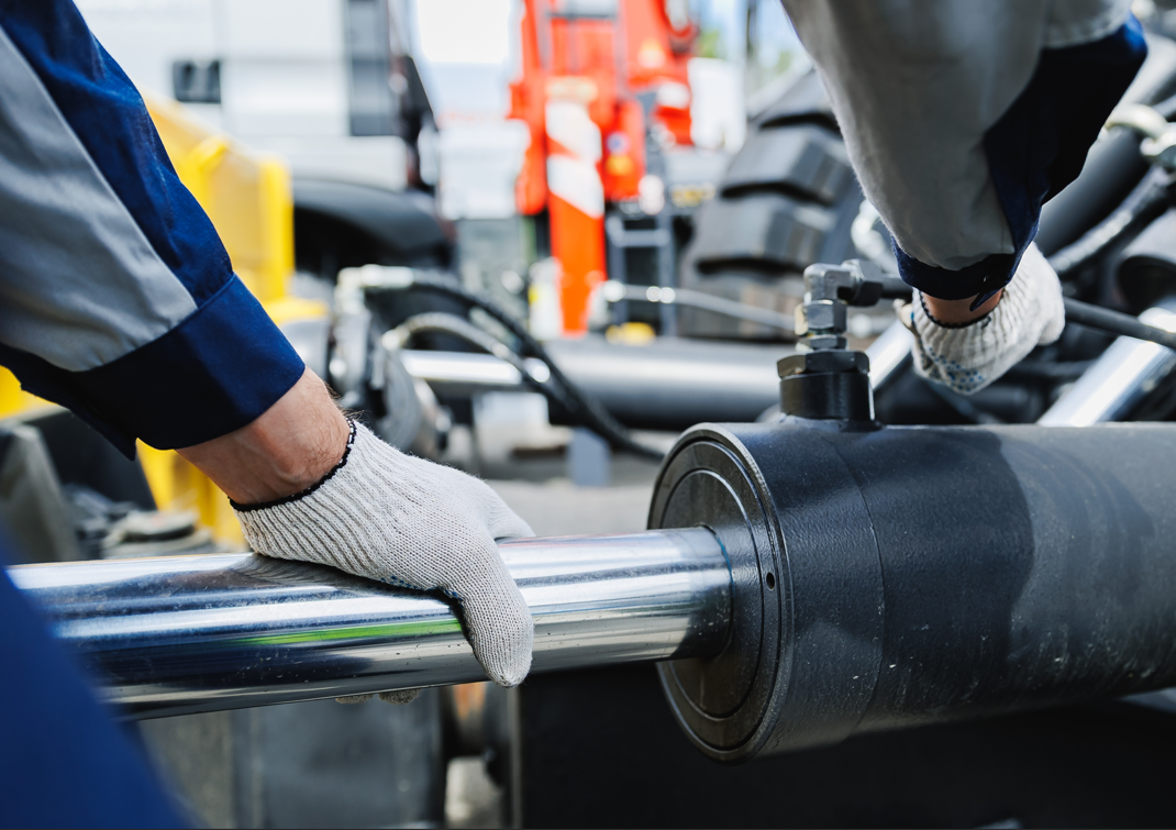 Close-up of a dark metal cylinder housing a metal rod. Orange background.