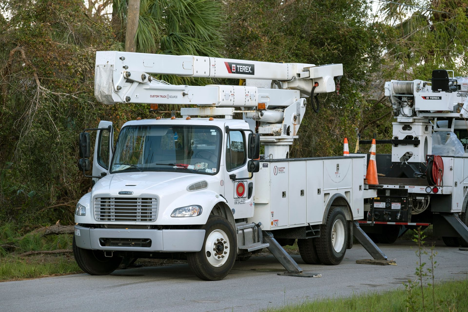 Orange dump truck on the road with a raised bed, against a blue sky and grassy verge.