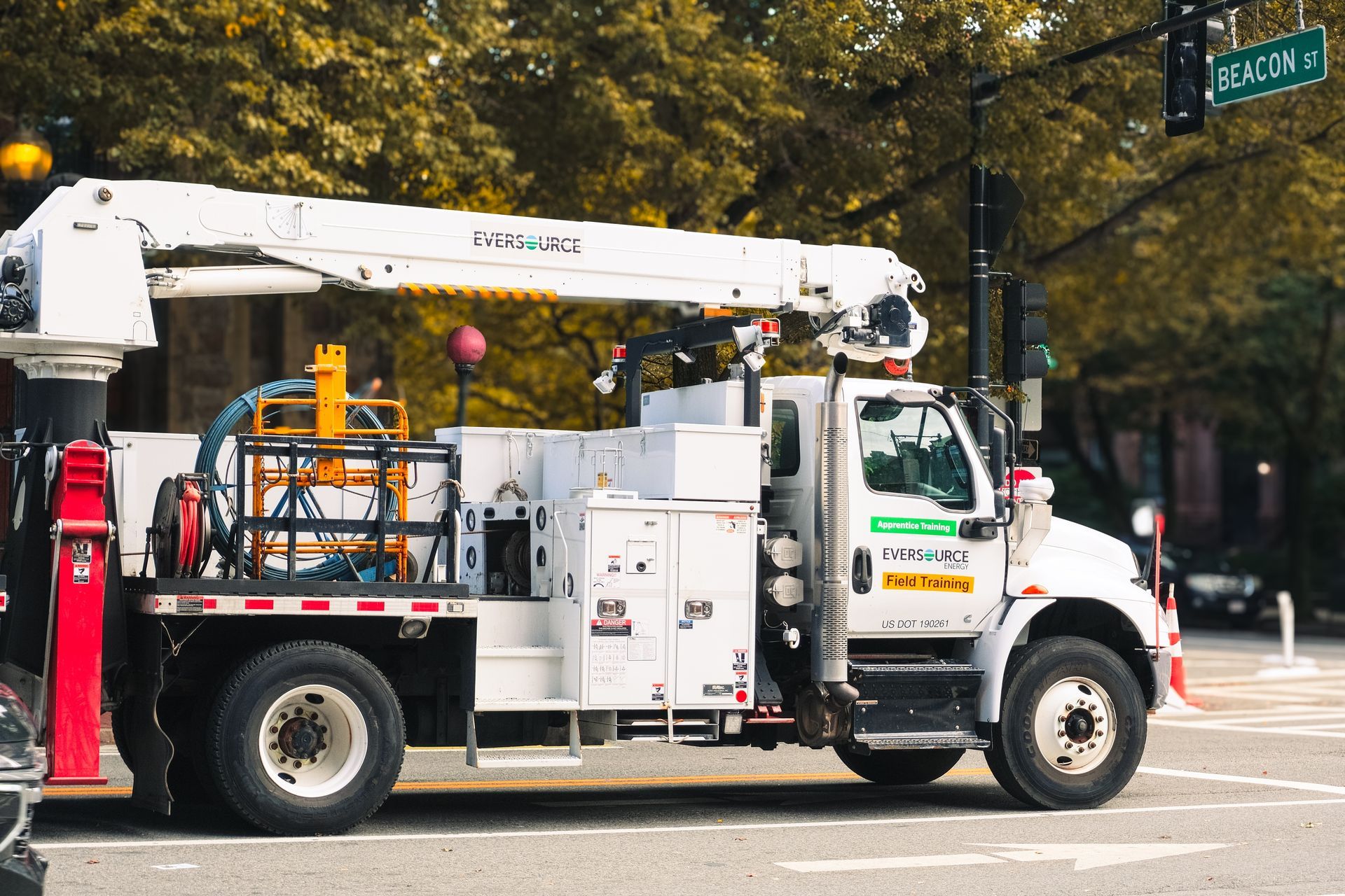Rear view of a gray dump truck bed, lifted. Two wheels and safety lights are visible.