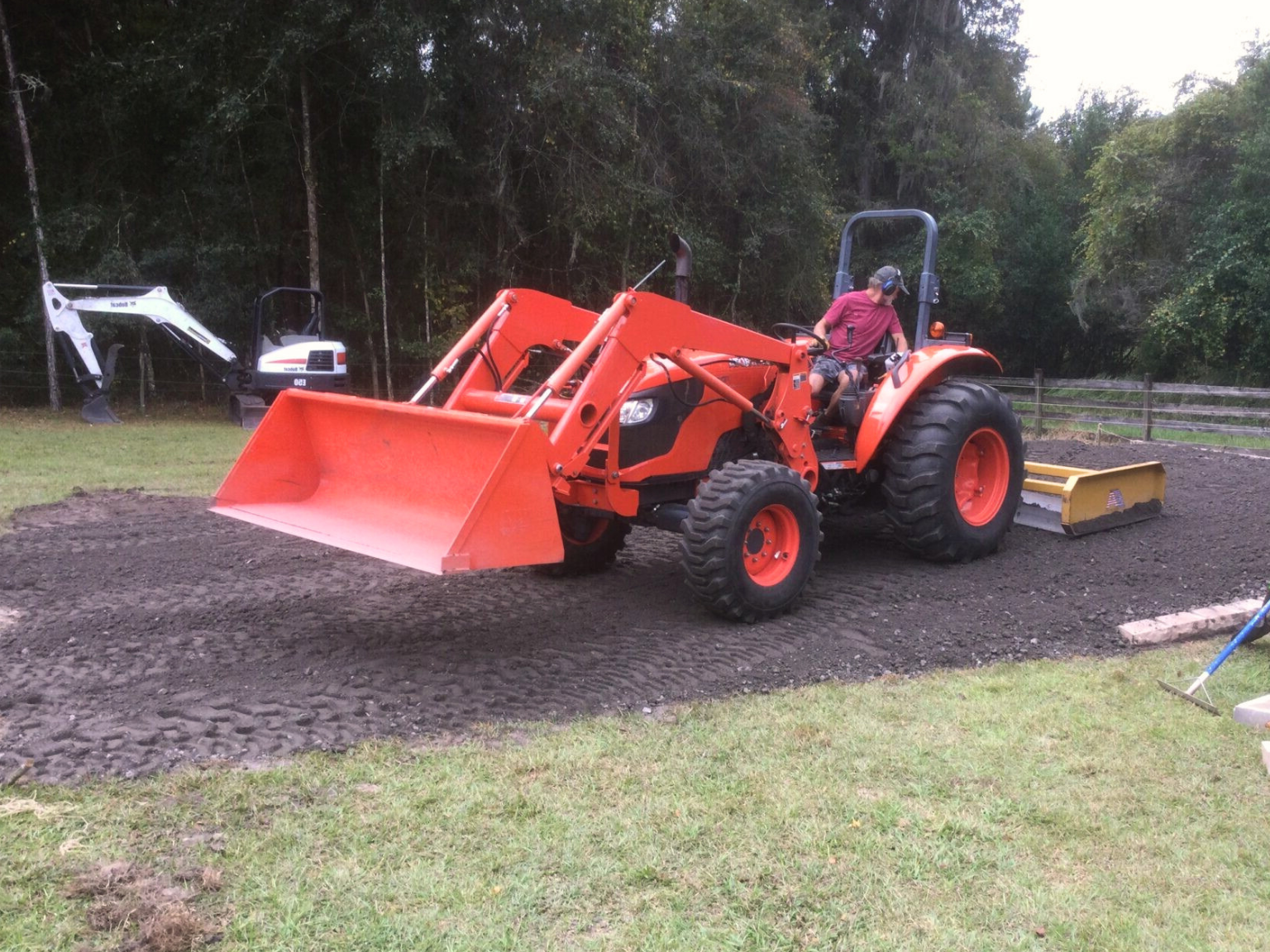A compact orange tractor is being used for light grading in a residential yard in Port St. Lucie.