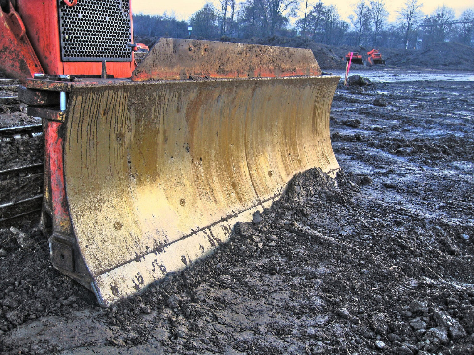 A close-up of a bulldozer blade working on a muddy construction site in Port St. Lucie, Florida.