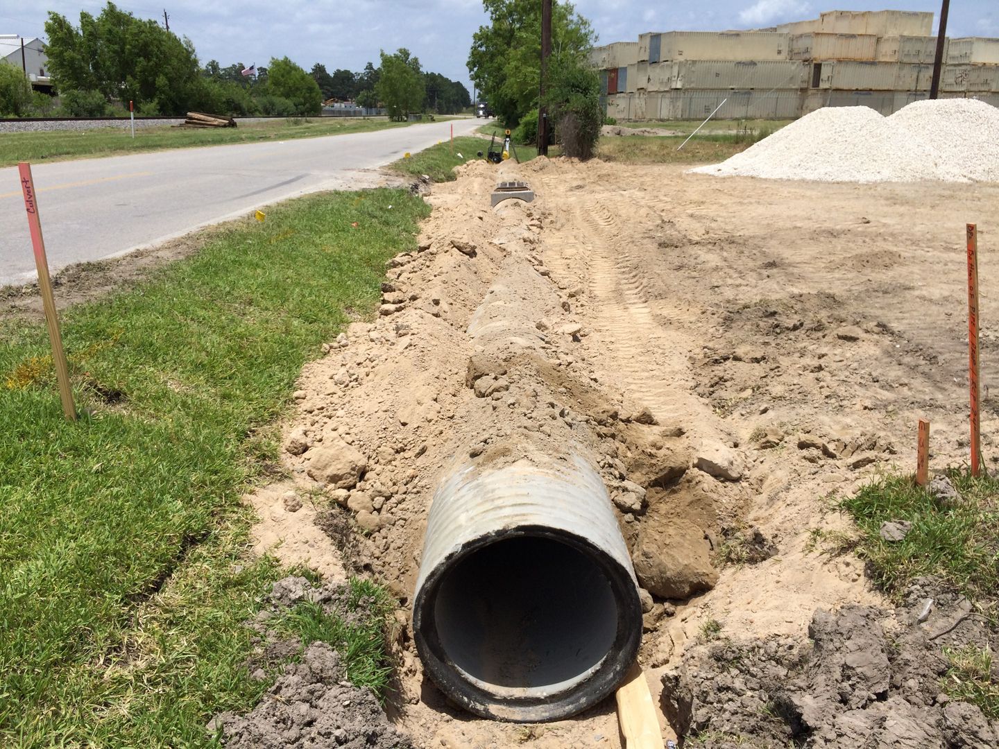 A bulldozer is digging a trench with a yellow hose attached to it.