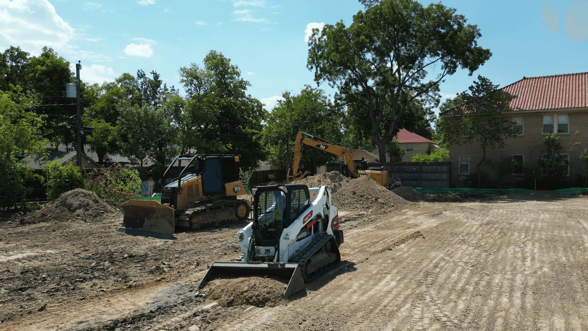 A bulldozer is digging a trench with a yellow hose attached to it.