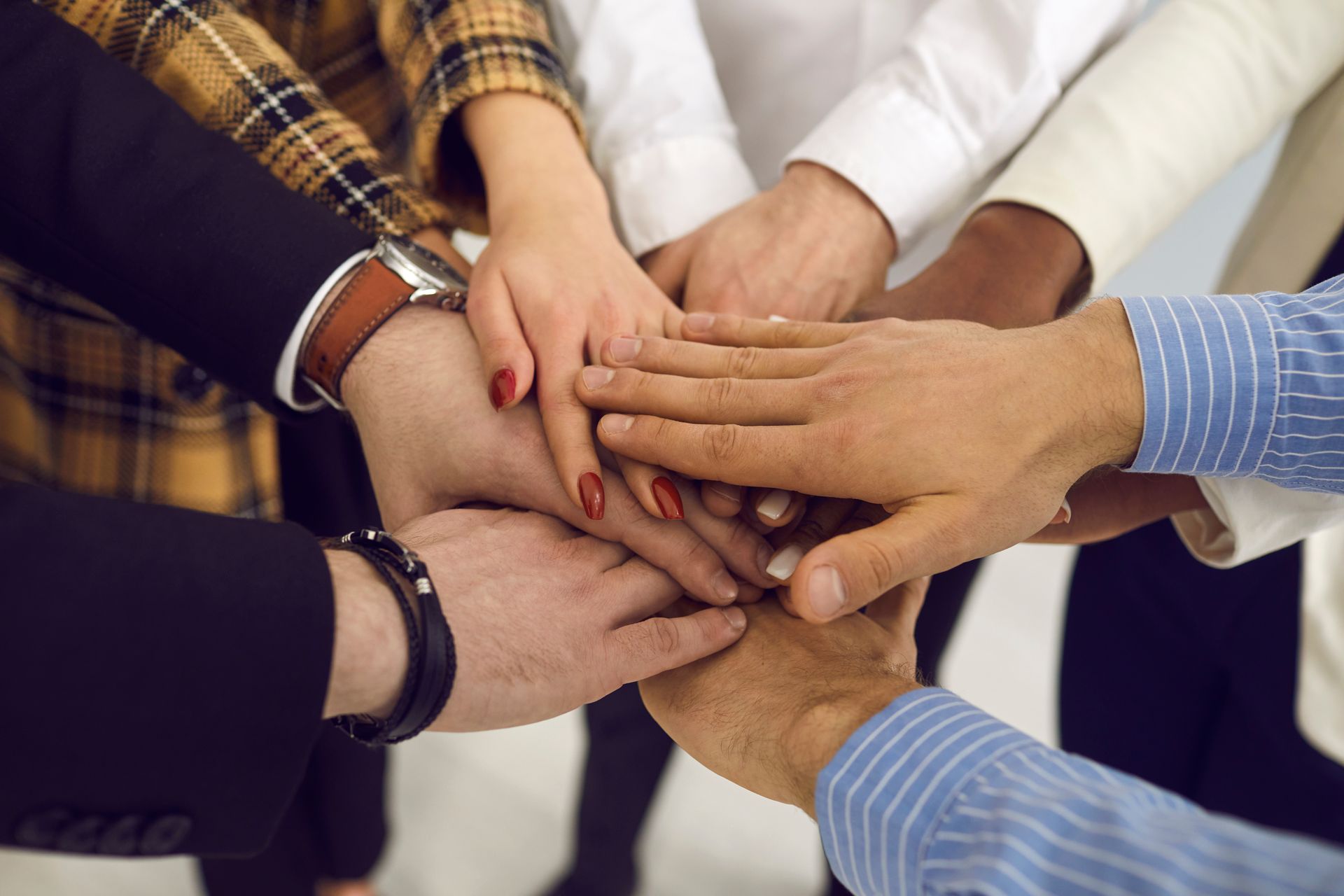 A diverse group of people stacking their hands together as a symbol of unity, teamwork, and collaboration.