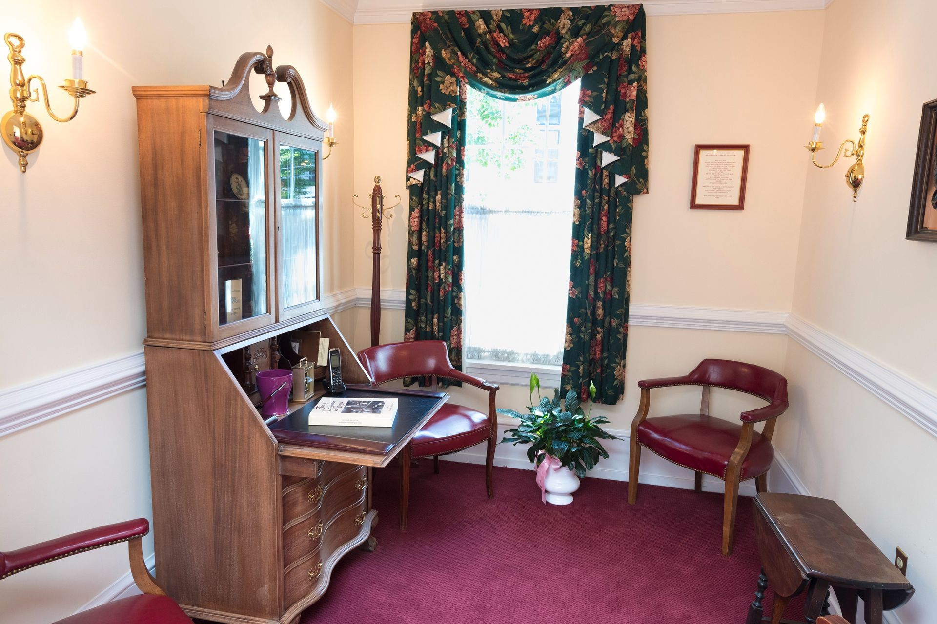 Cozy room with red carpet, wooden furniture, floral curtains, and a window seat by a bright window