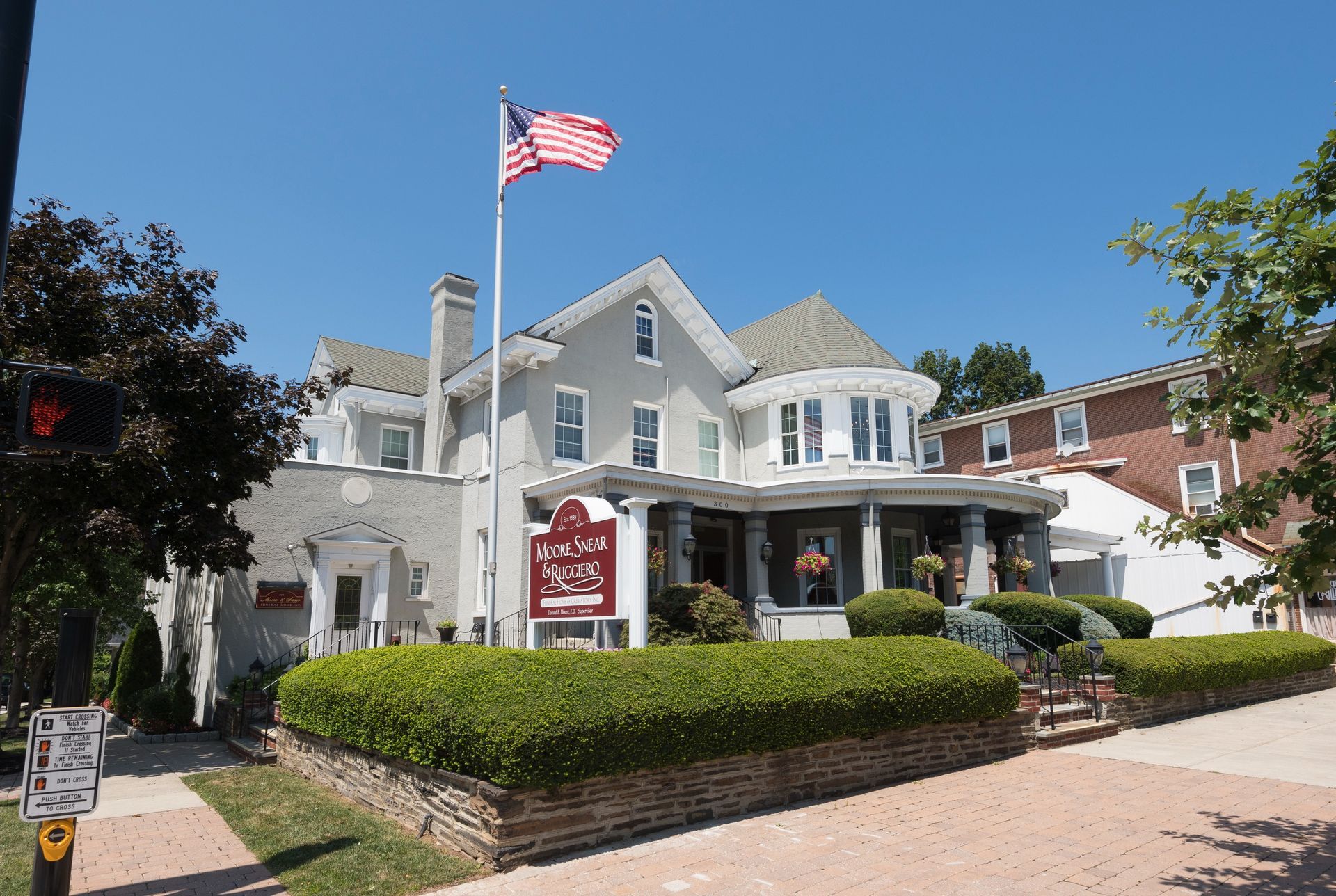 Historic white house with an American flag, porch, and sign under a bright blue sky
