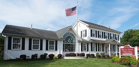 White two-story suburban house with a porch, black shutters, and a manicured lawn