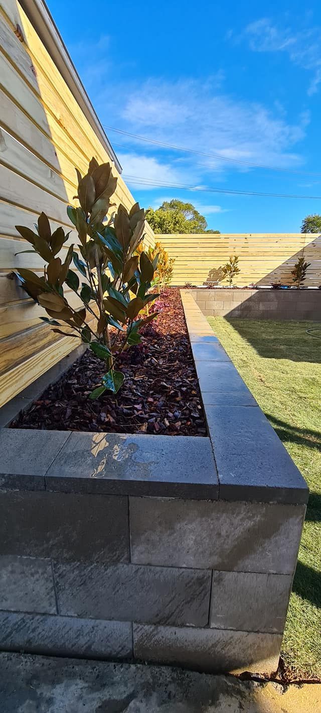 A planter with a plant in it is sitting next to a house.