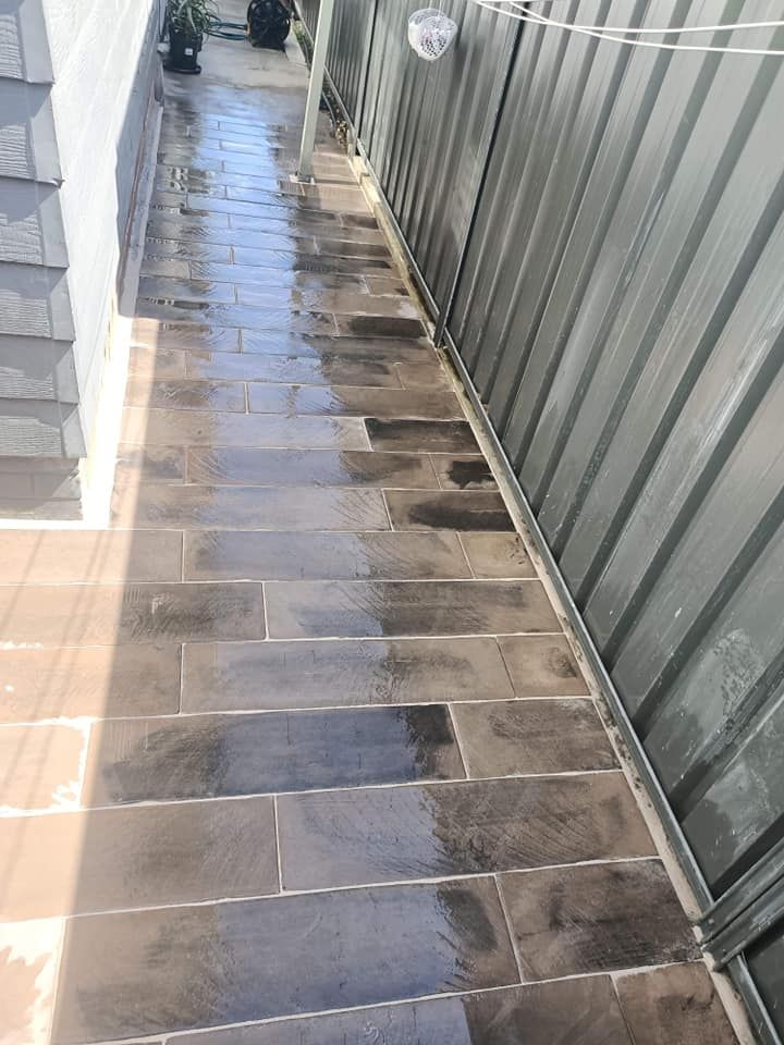 A sidewalk with tiles and a fence in the background.